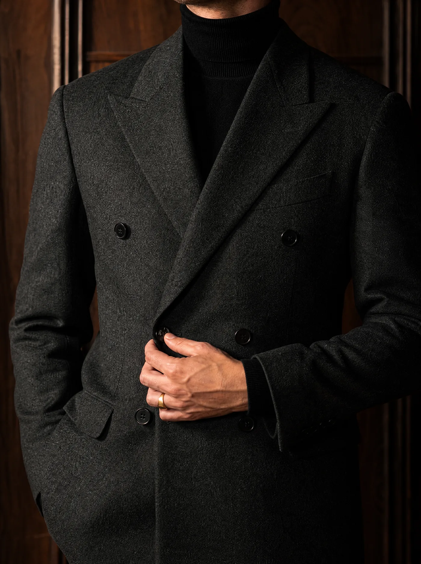 Close view of a charcoal double-breasted jacket over a black roll-neck
